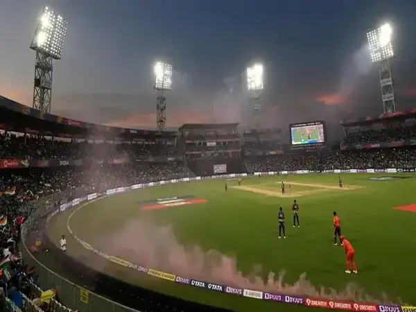 Cricket stadium lit by floodlights in the evening