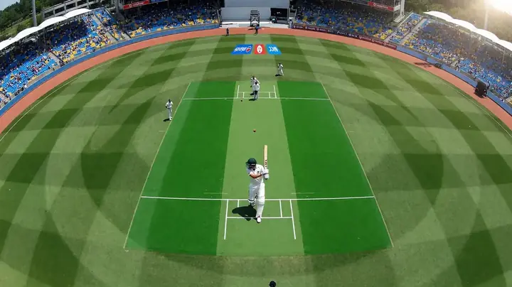 Aerial view of a green cricket pitch under bright daylight